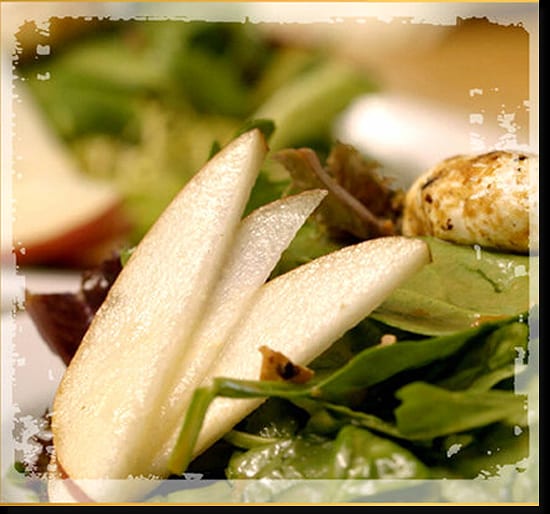 Sliced pear on greens beside goat cheese