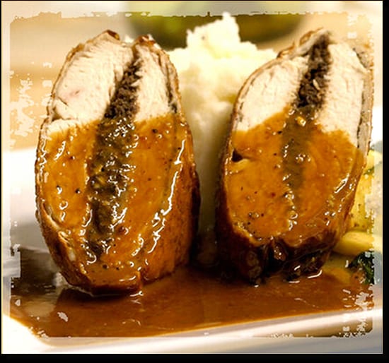 Two halves of a stuffed meat roll with gravy